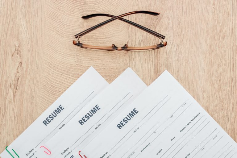 top view of resume templates and glasses on wooden surface