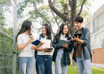 Young Asian college students and a female student group work at the campus park